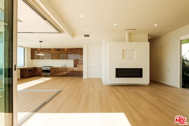 a view of kitchen and empty room with wooden floor