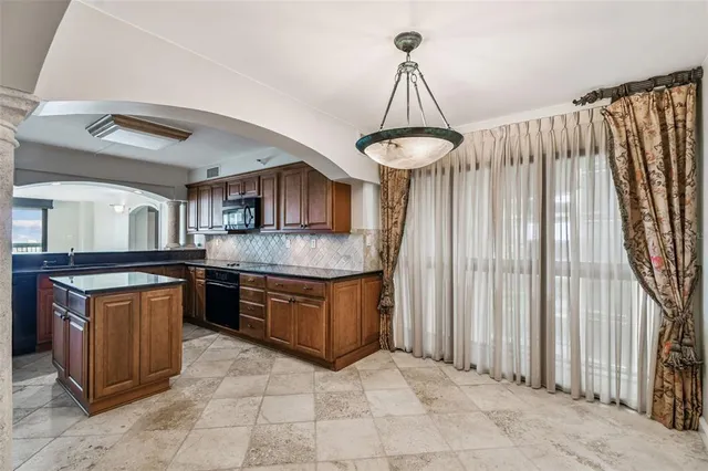 a kitchen with stainless steel appliances granite countertop a stove a sink dishwasher and a refrigerator with wooden cabinets