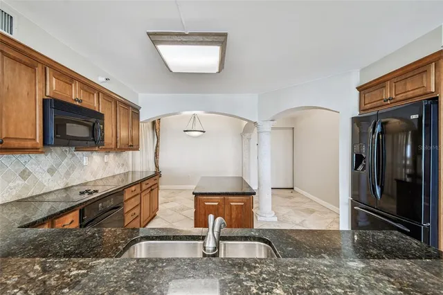 a living room with stainless steel appliances kitchen island granite countertop a refrigerator stove and sink