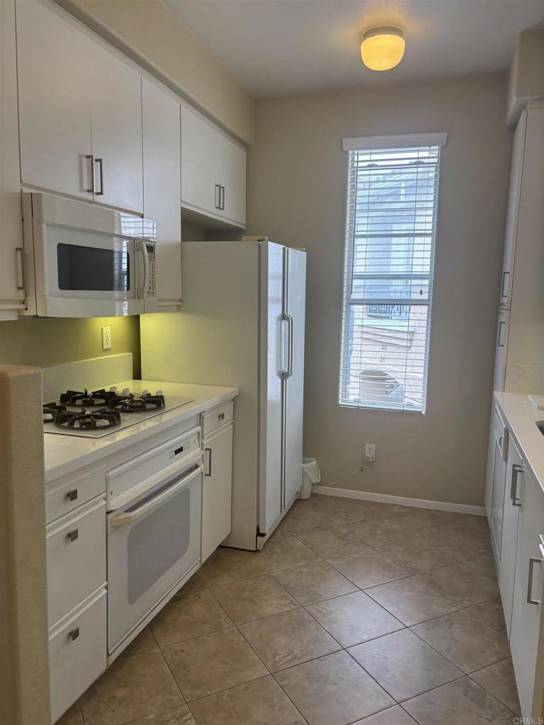 3575 Caminito El Rincon, Unit 216 San Diego, CA 92130 - Photo 7 of 14 a kitchen with stainless steel appliances granite countertop a stove a sink and a refrigerator