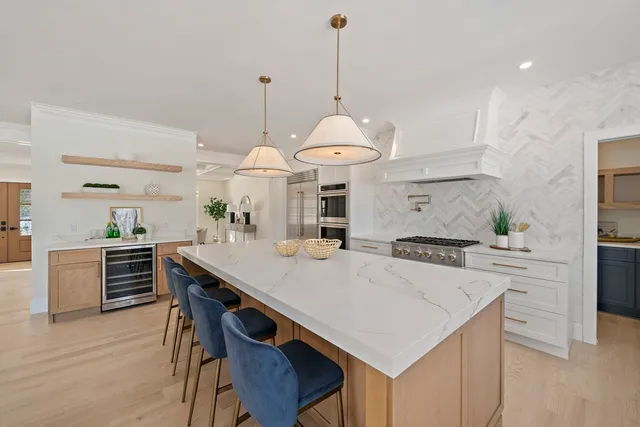 a kitchen with stainless steel appliances a stove a white center island and a refrigerator