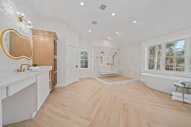 a spacious bathroom with a double vanity sink a large mirror and a bathtub