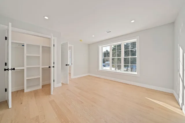 an empty room with wooden floor closet and windows