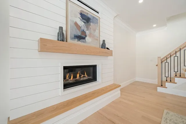 a view of an empty room with wooden floor and a fireplace
