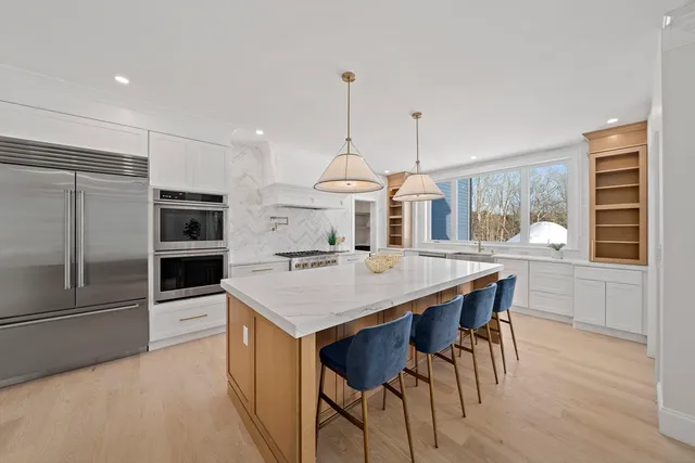 a kitchen with stainless steel appliances a dining table chairs and wooden floor