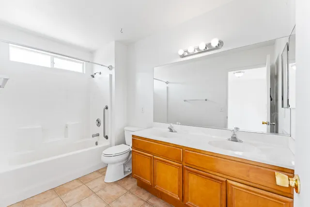 a bathroom with a granite countertop sink a toilet a mirror a bathtub and shower