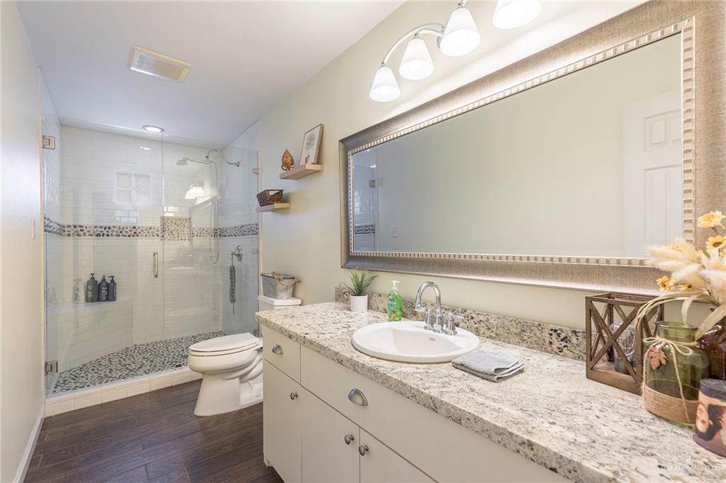 1902 Sundance Street Palmhurst, TX 78573 - Photo 25 of 43 a bathroom with a granite countertop sink a toilet a shower and a mirror