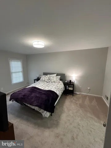 a spacious bedroom with a bed and a lamp