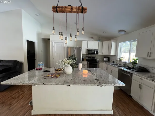 a kitchen with kitchen island granite countertop a sink and refrigerator