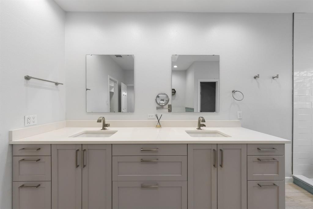 14140 Regency Place Dallas, TX 75254 - Photo 25 of 38 Dual vanity featuring light gray cabinetry with brushed nickel hardware, integrated rectangular sinks, and light-toned countertops