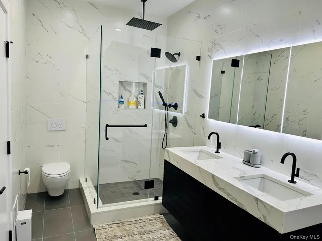a bathroom with a double vanity sink toilet mirror and shower