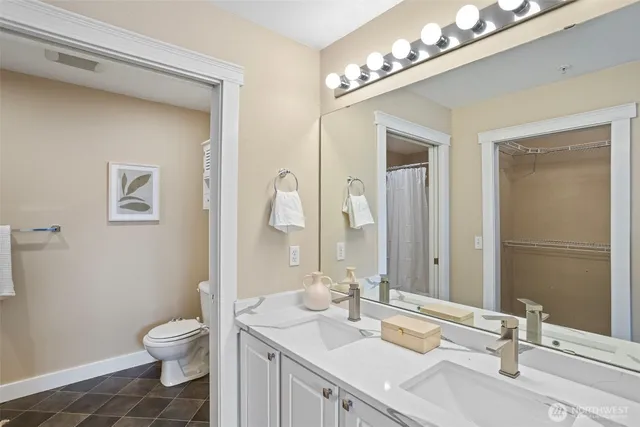 a bathroom with a granite countertop toilet a sink and a mirror
