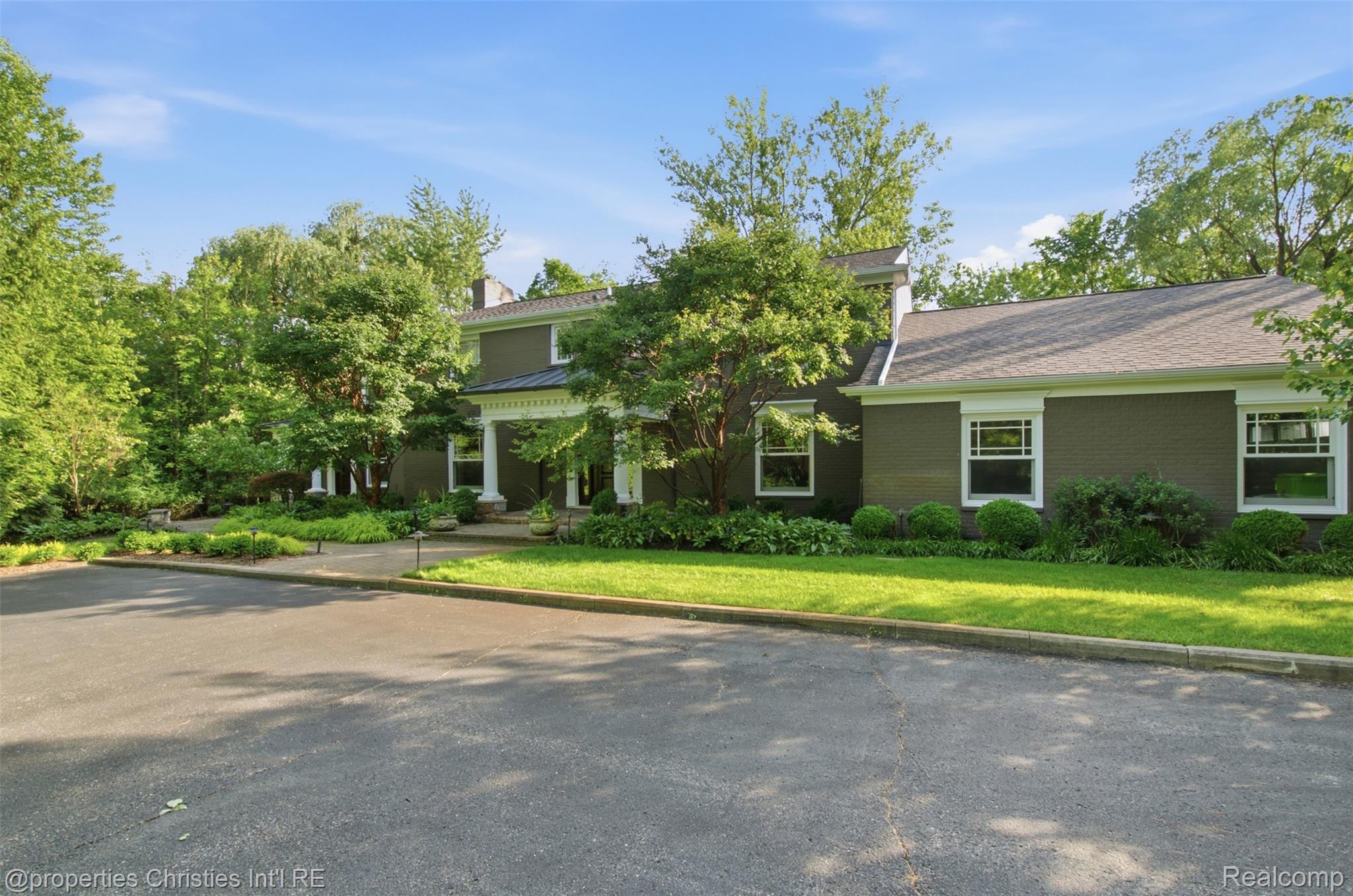 25235 Canterbury Road Franklin, MI 48025 - Photo 43 of 56 Expansive asphalt driveway leading to a brick-clad residence with a portico entry supported by columns