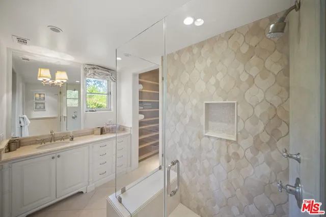 a spacious bathroom with a double vanity sink a large mirror and shower