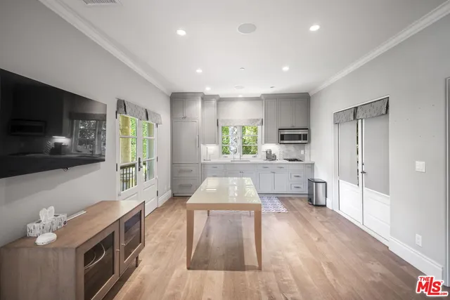 a living room with stainless steel appliances furniture wooden floor and a kitchen view