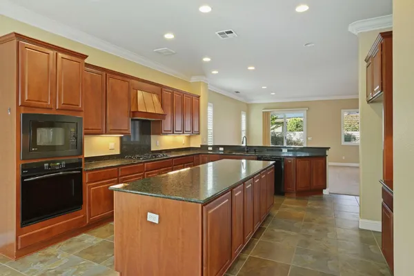 a kitchen with kitchen island granite countertop wooden cabinets a sink and stainless steel appliances