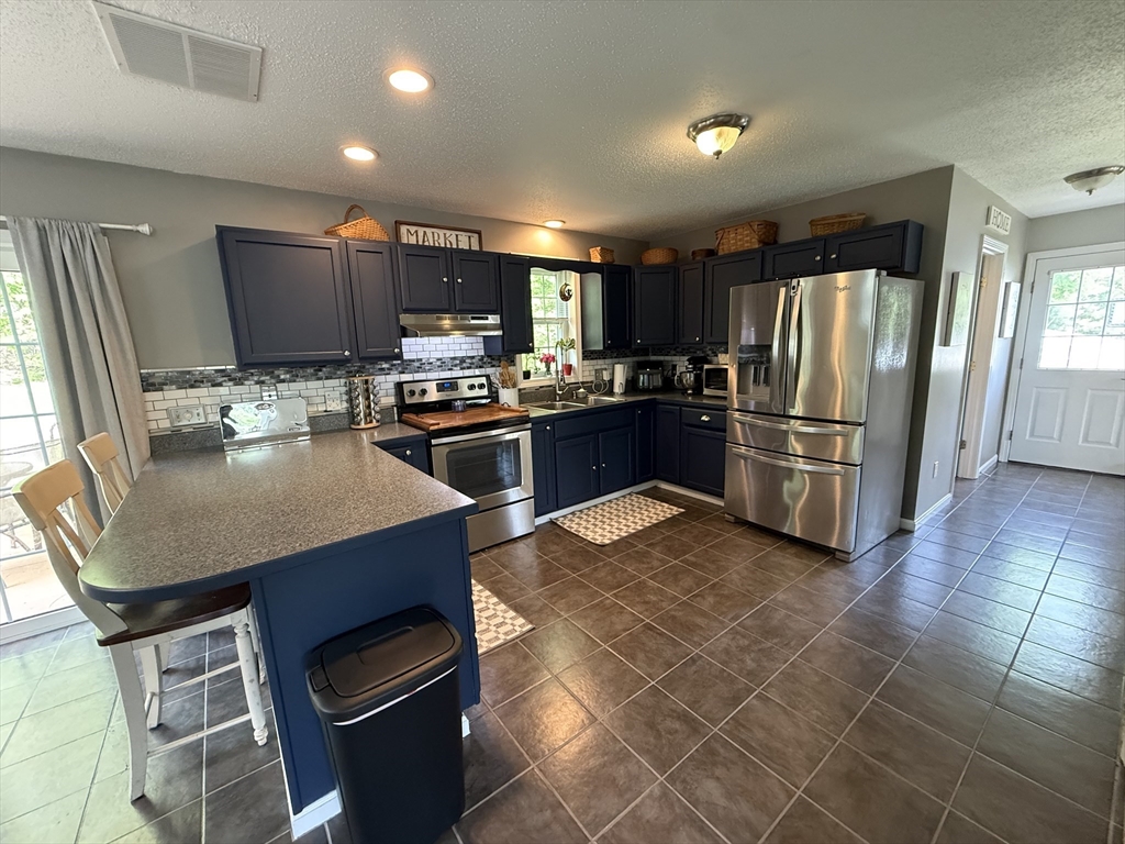222 Bridge Street Warren, MA 01083 - Photo 8 of 40 a kitchen with stainless steel appliances granite countertop a refrigerator a stove a sink a microwave and a dining table with wooden cabinet
