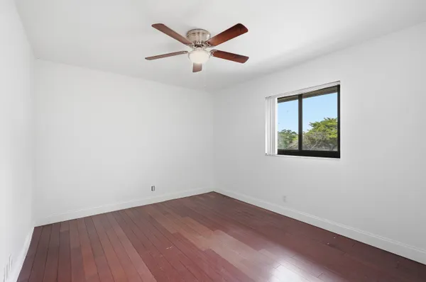 an empty room with wooden floor and ceiling fan
