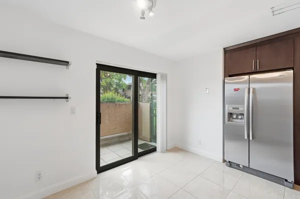 a view of a refrigerator in kitchen and an empty room