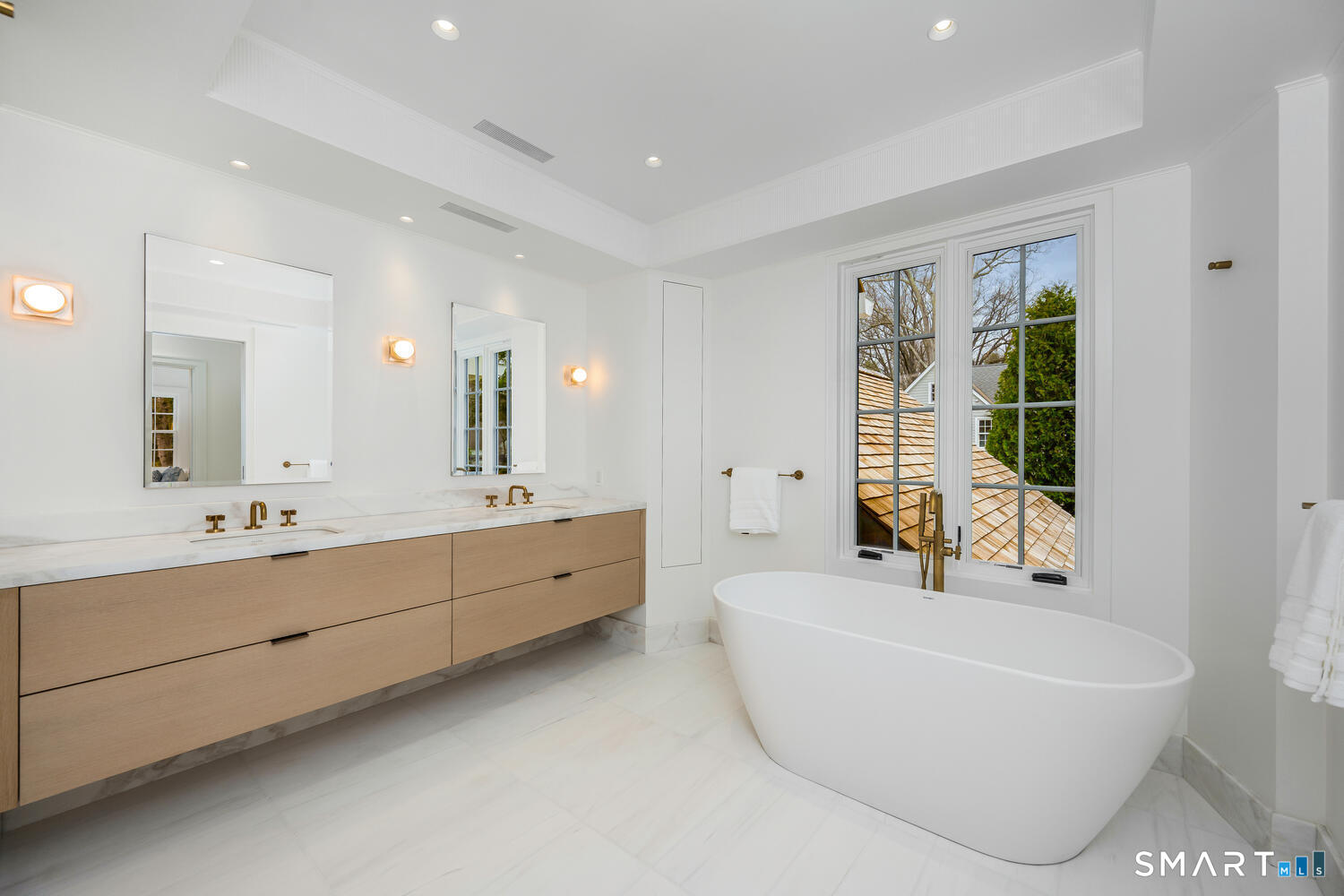 32 Birch Road Darien, CT 06820 - Photo 24 of 40 a bathroom with a bathtub a double vanity sink a toilet a window and mirror