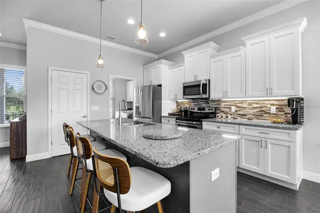 a kitchen with granite countertop stainless steel appliances a stove a sink a microwave a center island and a refrigerator