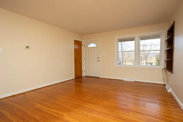 a view of an empty room with wooden floor and a window