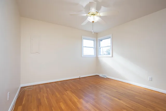 an empty room with a chandelier fan and windows