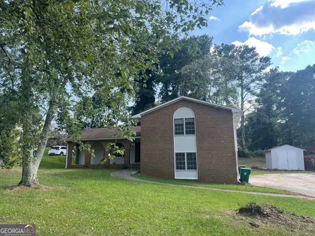a front view of a house with a garden and trees