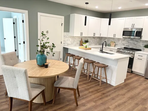 a kitchen with stainless steel appliances granite countertop a dining table chairs a sink dishwasher and a refrigerator