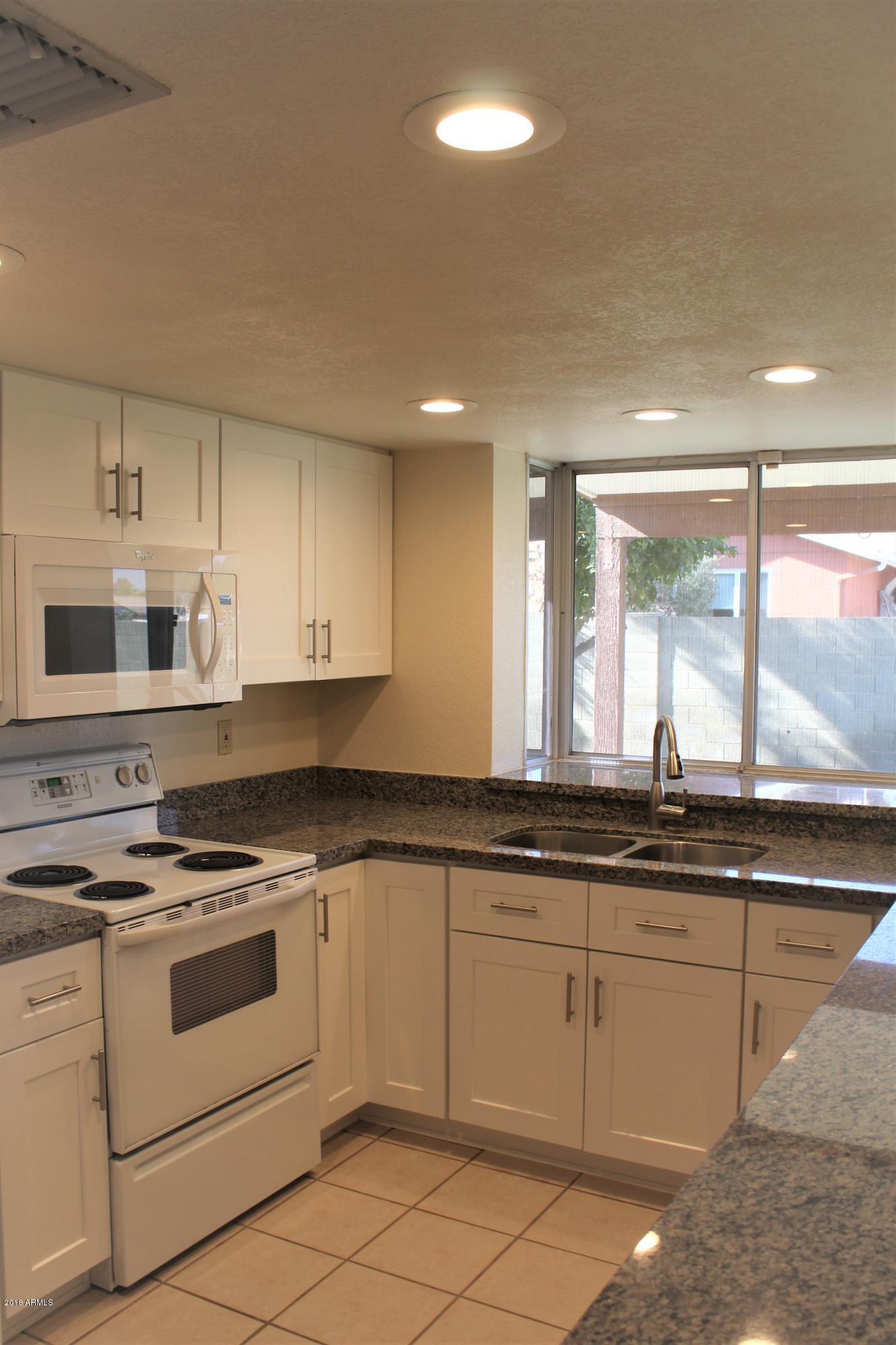 5940 East Spring Road Scottsdale, AZ 85254 - Photo 8 of 23 a kitchen with granite countertop white cabinets and white appliances