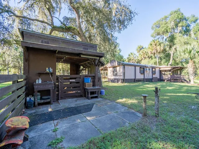 a view of a yard with a slide trees and wooden fence