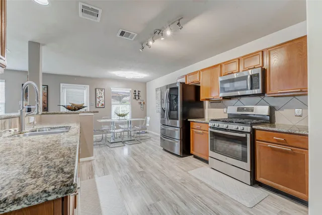 a kitchen with stainless steel appliances granite countertop wooden cabinets a stove top oven a sink and dishwasher