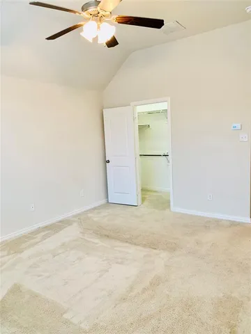 an empty room with a chandelier fan and closet