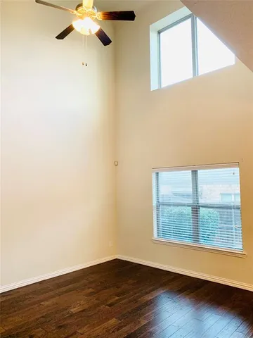 an empty room with wooden floor fan and windows
