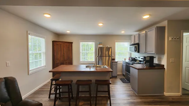 a kitchen with stainless steel appliances granite countertop a stove a refrigerator a kitchen island and chairs in it