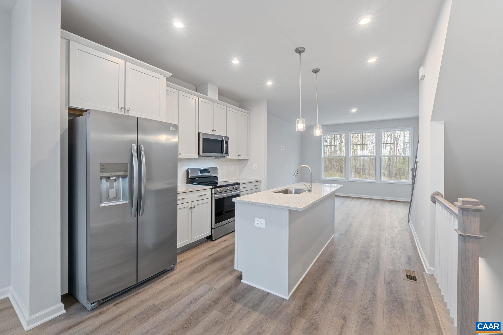 a kitchen with a sink a refrigerator and a stove top oven with wooden floor
