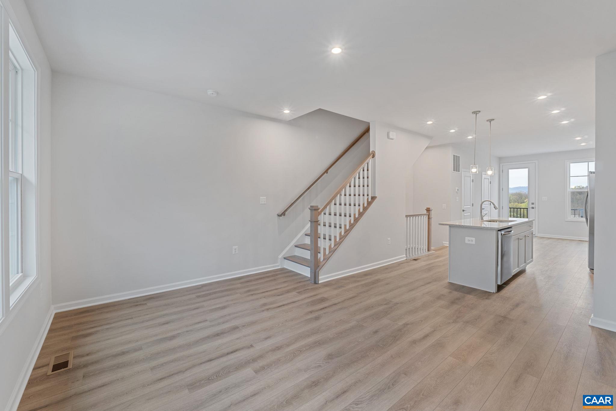 2249 Woodburn Road Charlottesville, VA 22901 - Photo 11 of 34 a view of an empty room with wooden floor and a kitchen