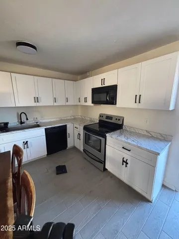 a kitchen with stainless steel appliances granite countertop a sink dishwasher a stove and white cabinets