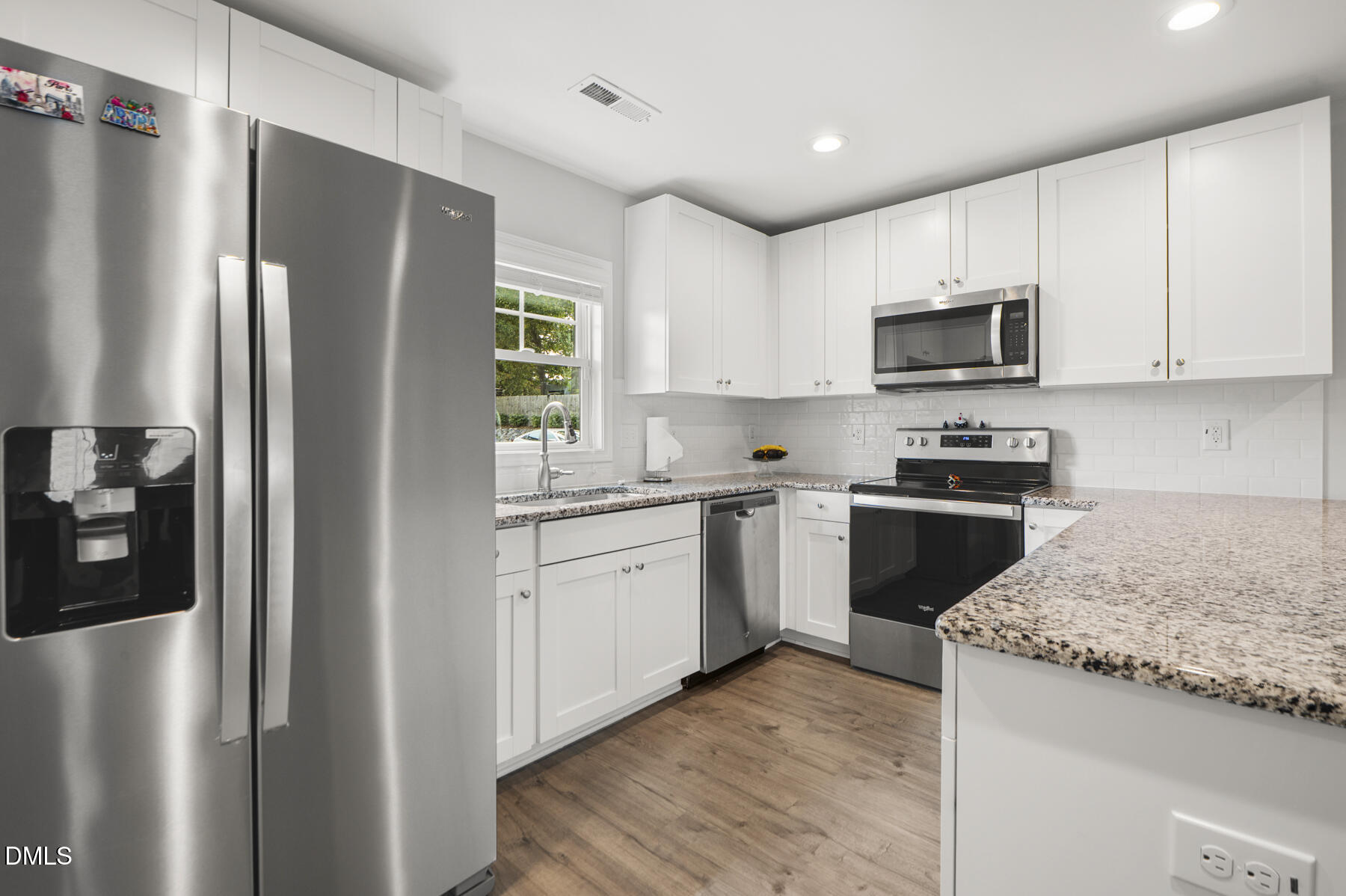 242 South Raleigh Street Angier, NC 27501 - Photo 5 of 31 Kitchen featuring stainless steel appliances, white cabinetry, granite countertops, tile backsplash, and lvp flooring