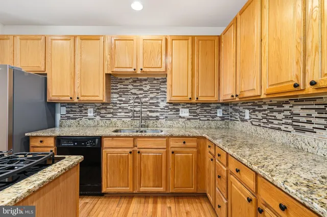 a kitchen with granite countertop a sink a refrigerator and cabinets