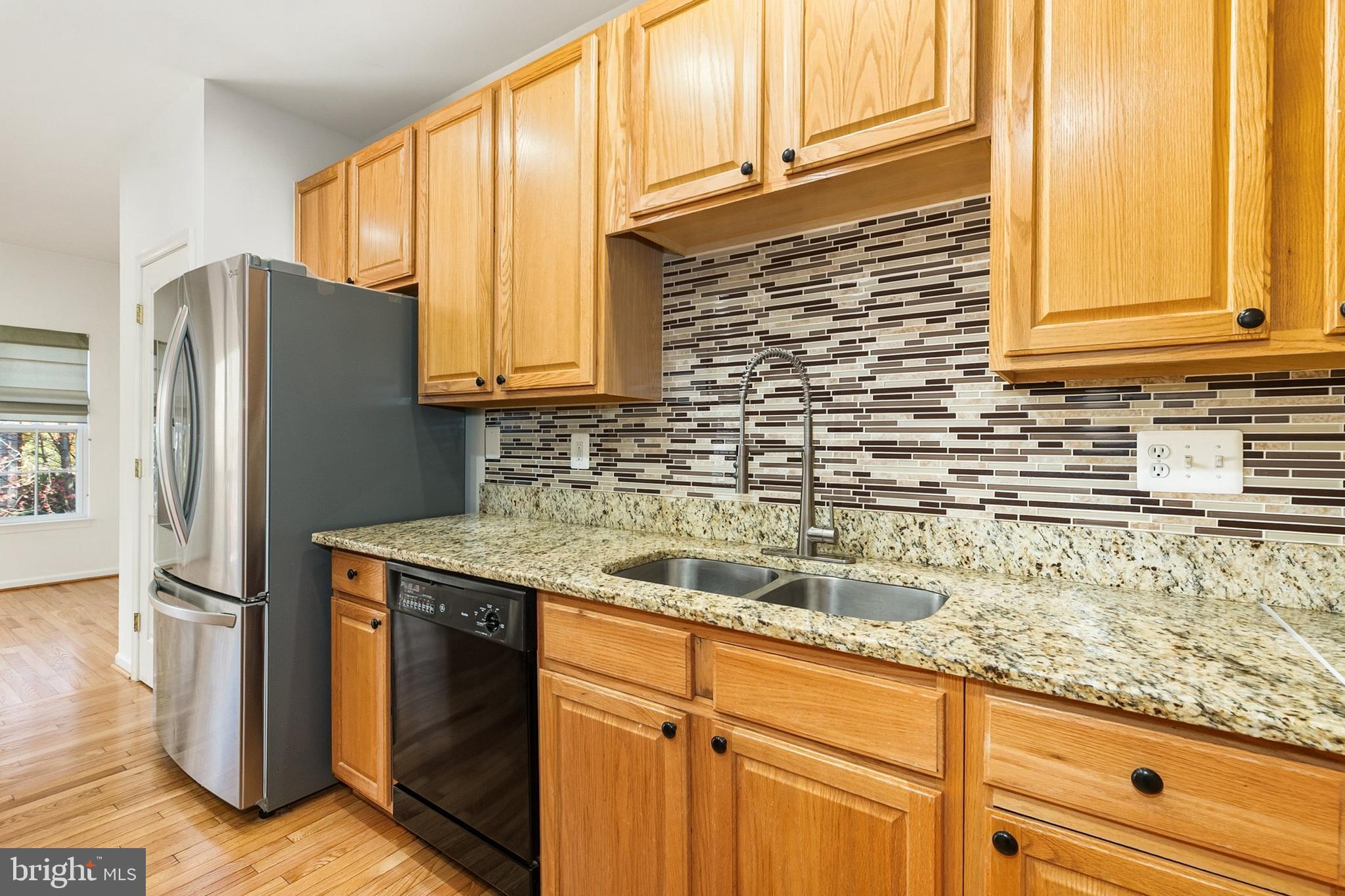 9956 Fragrant Lilies Way Laurel, MD 20723 - Photo 12 of 60 a kitchen with granite countertop a sink a refrigerator and cabinets