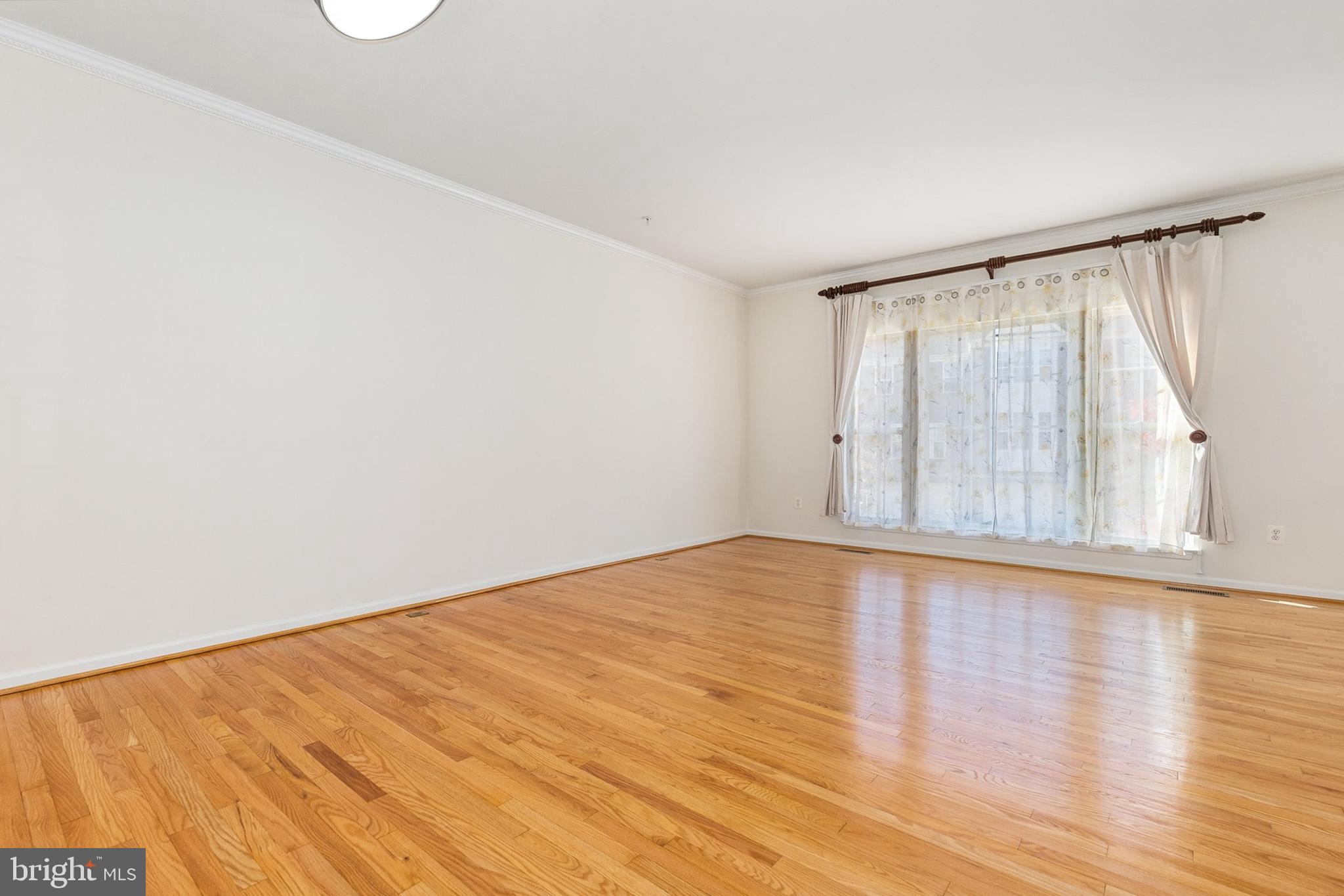 9956 Fragrant Lilies Way Laurel, MD 20723 - Photo 21 of 60 a view of an empty room with wooden floor and a window