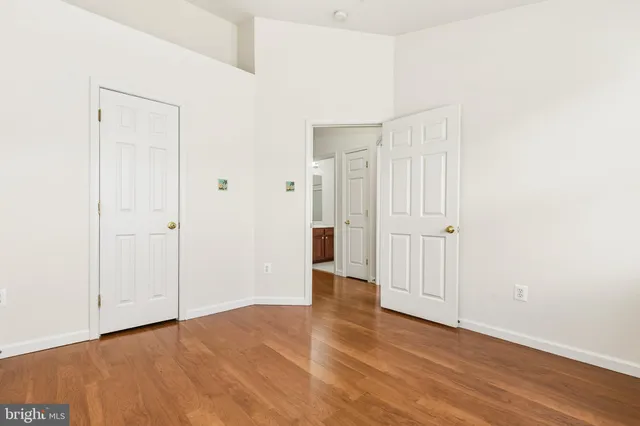 an empty room with wooden floor and a ceiling fan