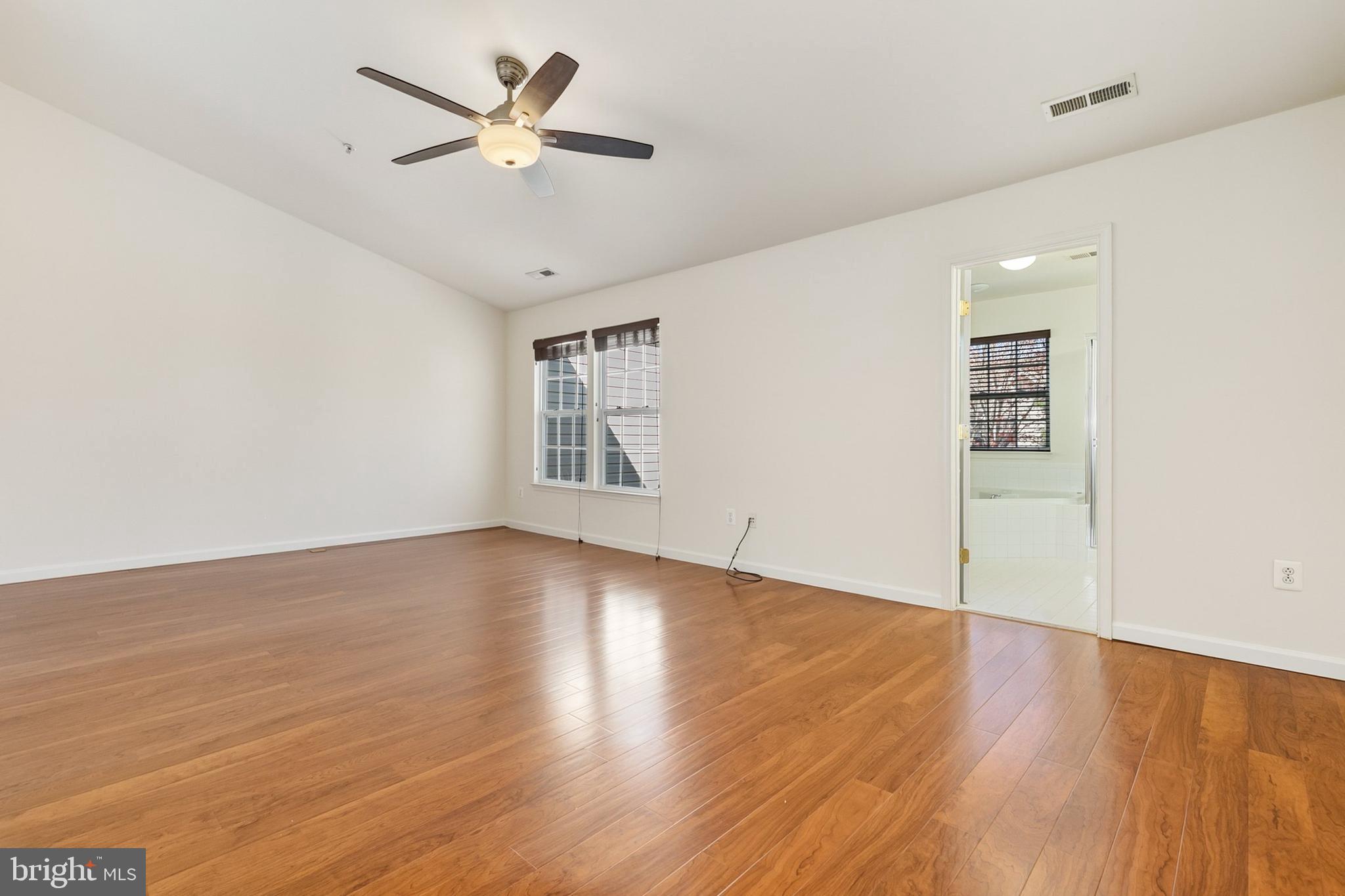 9956 Fragrant Lilies Way Laurel, MD 20723 - Photo 30 of 60 an empty room with wooden floor chandelier fan and windows