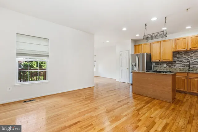 a view of kitchen with kitchen island wooden floor center island and stainless steel appliances