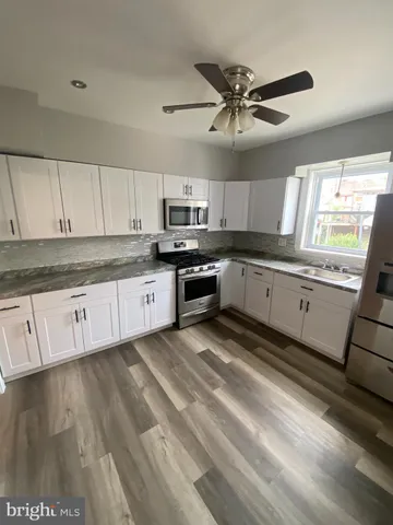 a kitchen with stainless steel appliances granite countertop a sink a stove top oven a chimney cabinets and a window