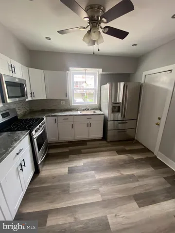 a kitchen with granite countertop a refrigerator and white cabinets