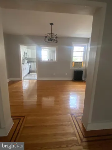 a view of empty room with wooden floor and window
