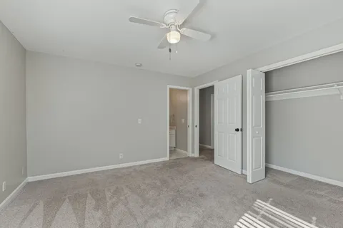 a view of an empty room and a ceiling fan & windows