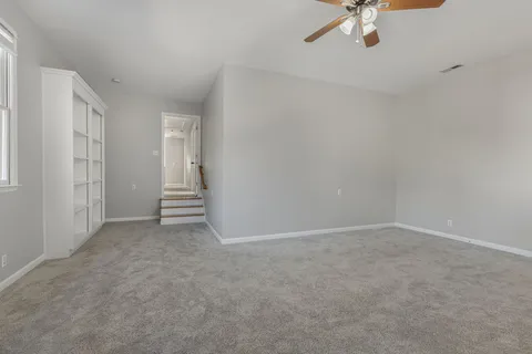 a view of an empty room with a chandelier fan